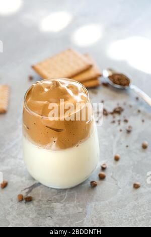 Dalgona Coffee Cream with milk in glass cup with spoon in the background Stock Photo