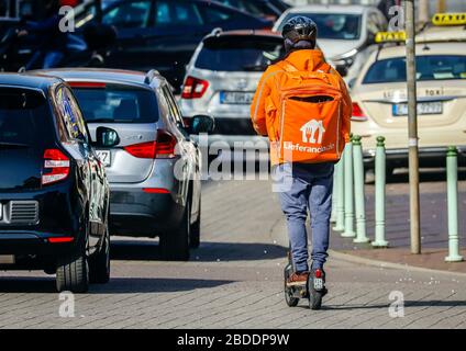 27.03.2020, Essen, North Rhine-Westphalia, Germany - Lieferando Lieferdienst, a courier driver on an electric scooter delivers ordered food. 00X200327 Stock Photo