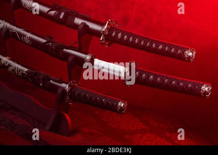Stand with swords, middle one partially exposed, red light Stock Photo