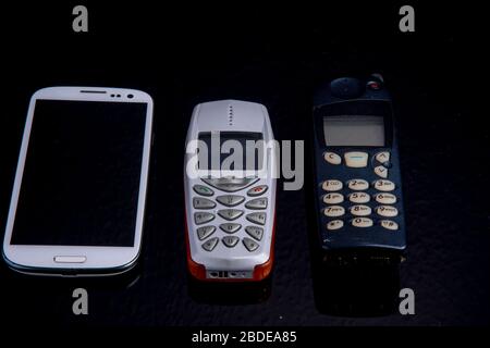 Three mobile phone generations side by side from old to smartphone Stock Photo