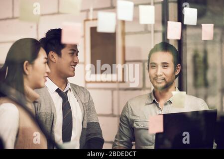 three asian small company businesspeople young entrepreneurs meeing discussing in office using sticky notes Stock Photo