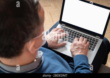 Rear view shot of man working on laptop from home. Remote home office. Self isolation. Close up. Space on screen. Stock Photo