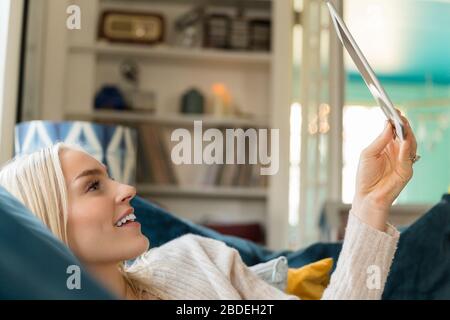 Woman using tablet while lying on sofa Stock Photo