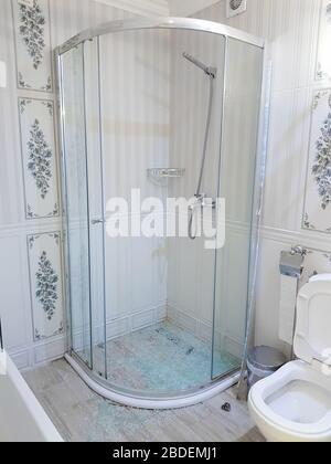 Shattered tempered glass cleanup after a shower door explodes in a hotel room. Stock Photo