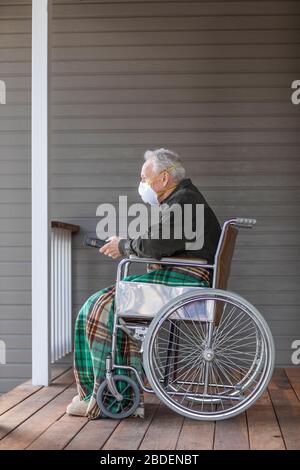 Senior man in wheelchair wearing protective mask to preventÂ coronavirusÂ transmission on porch Stock Photo