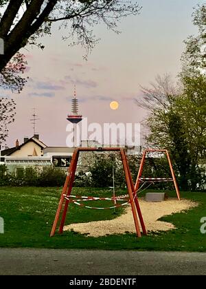 Frankfurt am main in time of  Corona virus covid-19. TV tower Europa from Park by Nidda river Nidda in the evening with full moon Stock Photo