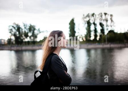 Woman walking near lake in cloudy weather Stock Photo