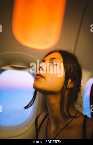 Portrait of young woman in plane illuminated with sunset light Stock Photo