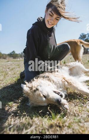 Young woman playing on grass with dog from animal shelter Stock Photo