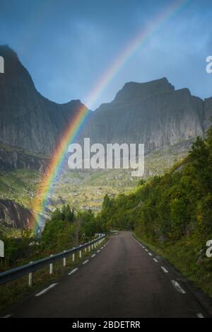 Norway, Lofoten Islands, Rainbow above empty road in mountain landscape Stock Photo