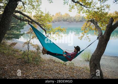 Italy, Man lying in hammock near lake Stock Photo
