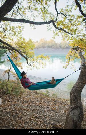 Italy, Man lying in hammock near lake Stock Photo