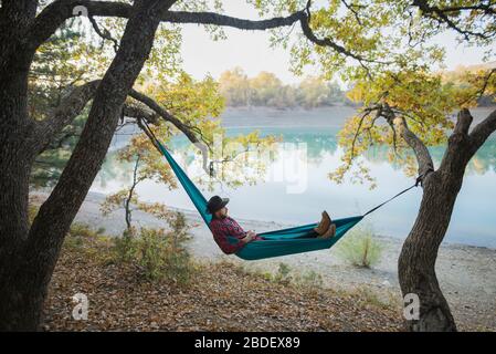 Italy, Man lying in hammock near lake Stock Photo