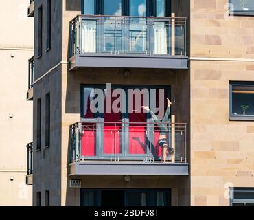 Leith, Edinburgh, Scotland, UK. 8th Apr, 2020. Covid-19 lockdown: on one of the warmest sunny days so far this year with people in lockdown. A woman practices acrobatic handstands on a balcony in the sunshine Stock Photo