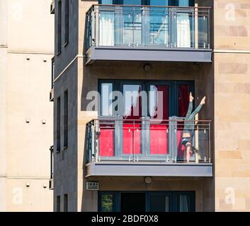 Leith, Edinburgh, Scotland, UK. 8th Apr, 2020. Covid-19 lockdown: on one of the warmest sunny days so far this year with people in lockdown. A woman practices acrobatic handstands on a balcony in the sunshine Stock Photo