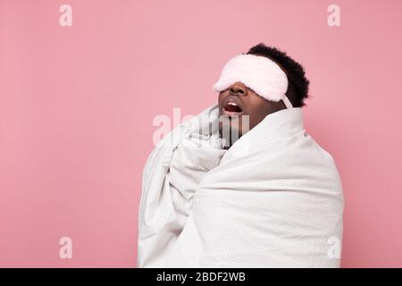 Sleepy dark haired man in medical mask holding white blanket Stock Photo