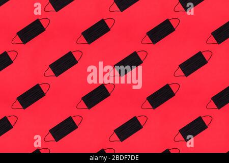 Many black protective masks on the red colored background. Epidemic concept. Stock Photo