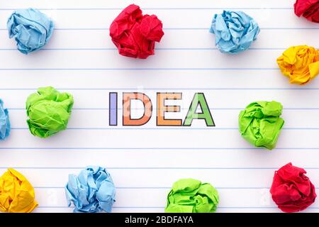 The word Idea written on a lined notebook sheet with some crumpled paper balls around it. Close up. Stock Photo