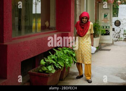 Elderly woman with thoughtful expression wearing colorful, traditional Indian clothes outside shop in street in Delhi, India. Stock Photo