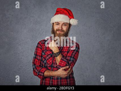 Young handsome smiling excited man in red santa hat isolated on gray grey background. Positive emotion and symbols Stock Photo