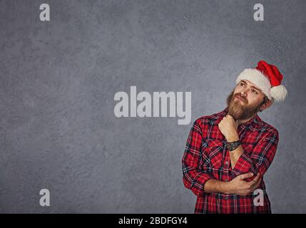 Bearded man thinking for christmas gift ideas isolated grey background Stock Photo