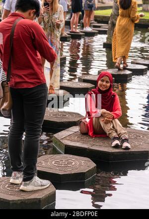 Vertical portrait of a couple on the stepping stones at Tirta Gangga water palace in Bali, Indonesia. Stock Photo