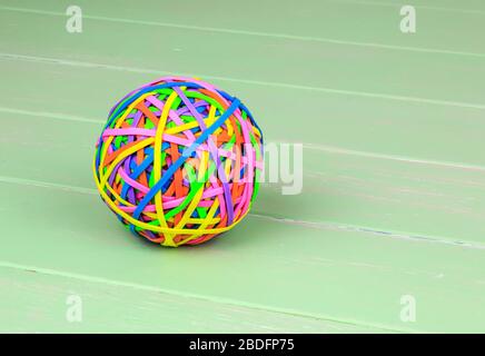Coloured ball of rubber bands on a green shabby board back ground Stock Photo