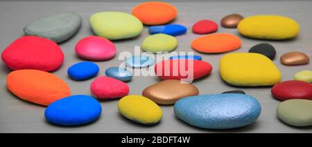 Multi coloured  stones lying on a light grey shabby background Stock Photo