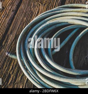 Coiled garden hose on wood decking Stock Photo