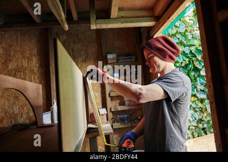 Carpenter using tape measure in shed Stock Photo
