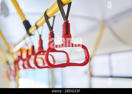 partially blurred grab handles for standing passengers in the passenger compartment of the bus close-up Stock Photo