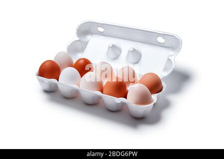 eggs of different shades from white to brown are packed together in one egg crate, isolated on a white background Stock Photo