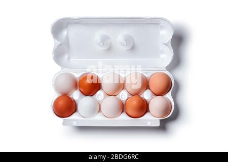 eggs of different shades from white to brown are packed together in one egg crate, isolated on a white background, horizontal top view, Stock Photo