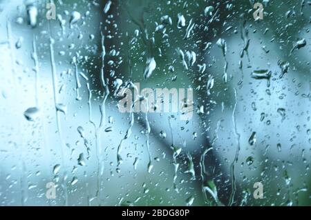 Blurred picture of traffic through a car window during heavy rain.Car glass with lots of rain drops during rain shower.City view through blurry window Stock Photo