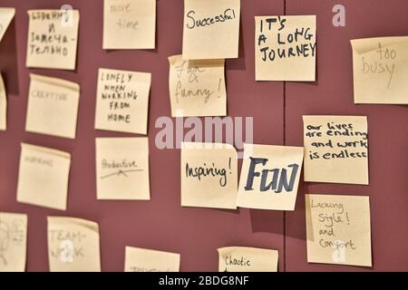 Wine-red wall with hanging yellow sticky notes Stock Photo