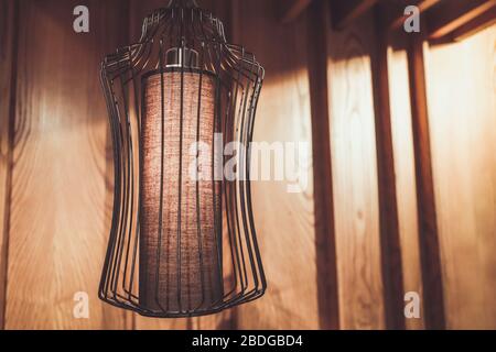 Close up of metal chandelier in loft interior against wooden wall. Stock Photo