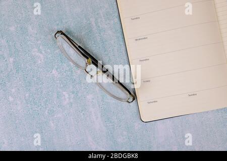 Top view with desk on lined notebook of reading glasses on table Stock Photo