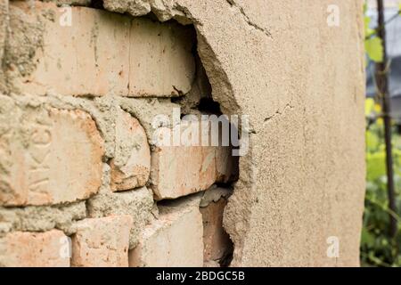 Non technology plaster. Building cracked plaster facade wall with brick. Stock Photo