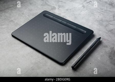 Graphic tablet with a stylus on a dark textural background, top view. Gadget for working as a designer, artist and photographer Stock Photo