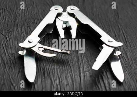 Multi-functional tool on a black textural background. Stock Photo