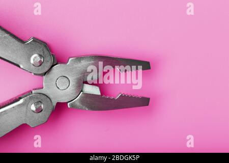 Multifunctional tool close-up on a pink background. The concept of a pocket tool with free space. Stock Photo