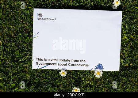 Letter from the British government explaining the need to stay indoors while the Covid-19 Corona virus is pandemic. On grass with daisy flowers.