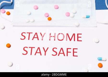 Coronavirus Pandemic Protection Concept. Words stay at home with medicine and medical mask. Minimal concept. Stay safe, concept of self quarantine at Stock Photo