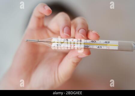 Girl holds a thermometer. High body temperature on a thermometer.  Stock Photo