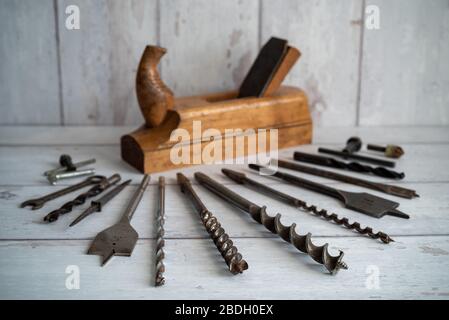 Vintage tools. Vintage drill bits with vintage wood planer against a white wooden background Stock Photo
