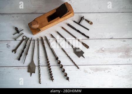 Vintage tools. Vintage drill bits with vintage wood planer against a white wooden background Stock Photo