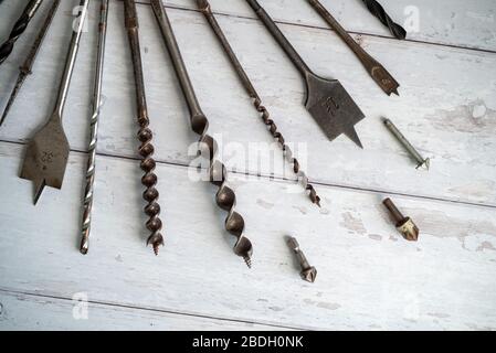 Vintage tools. Vintage drill bits against a white wooden background Stock Photo