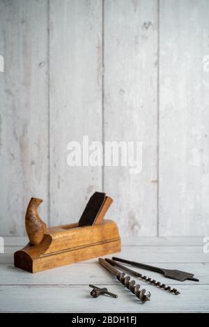Vintage tools. Vintage drill bits with vintage wood planer against a white wooden background Stock Photo