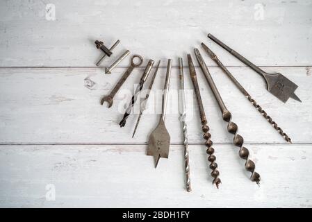 Vintage tools. Vintage drill bits against a white wooden background Stock Photo