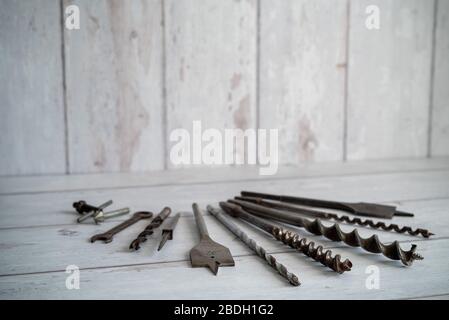 Vintage tools. Vintage drill bits against a white wooden background Stock Photo